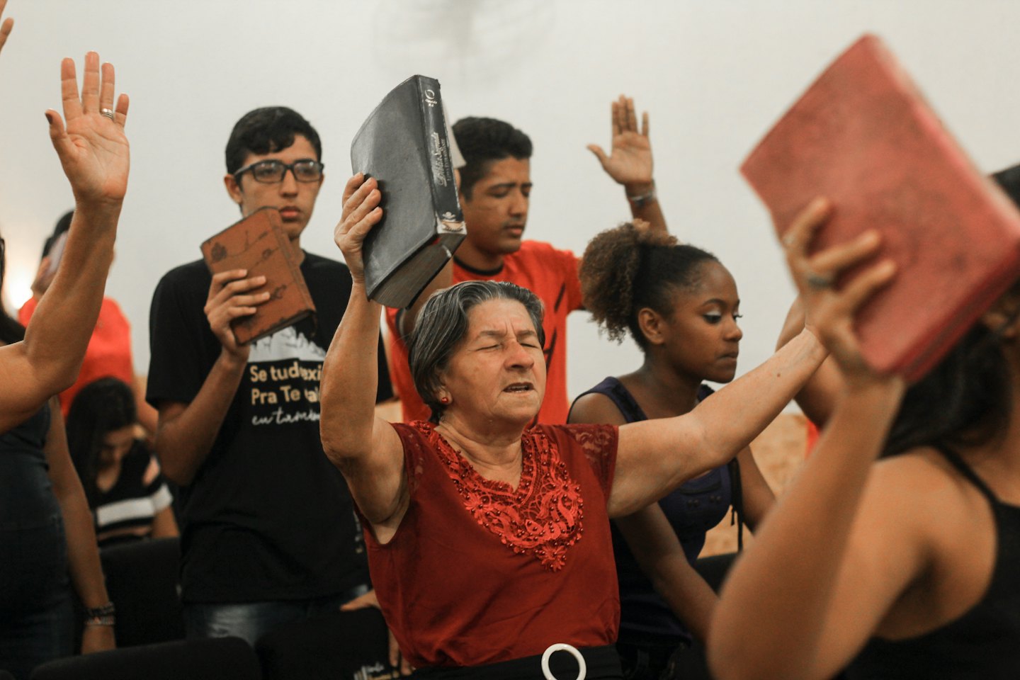 People gathered indoors with hands raised in worship.