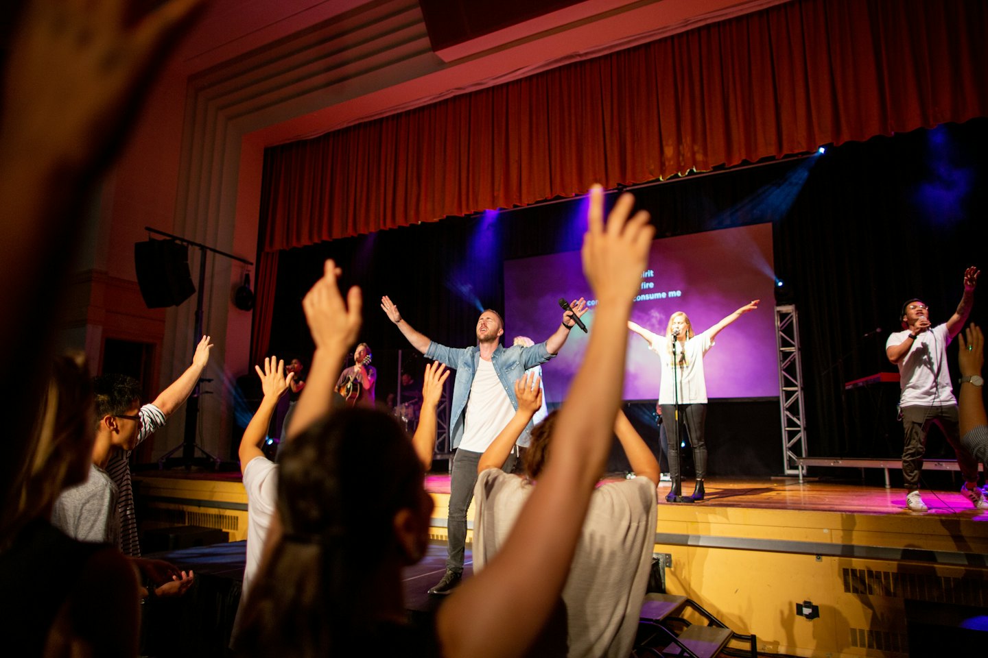 People raising hands during an energetic indoor concert.