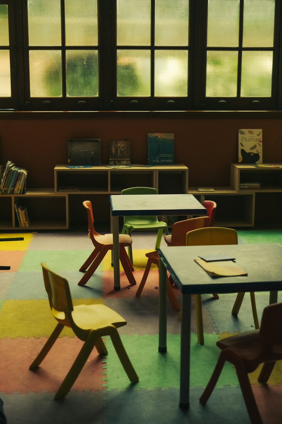 Children's classroom with colorful tables and chairs on foam floor.